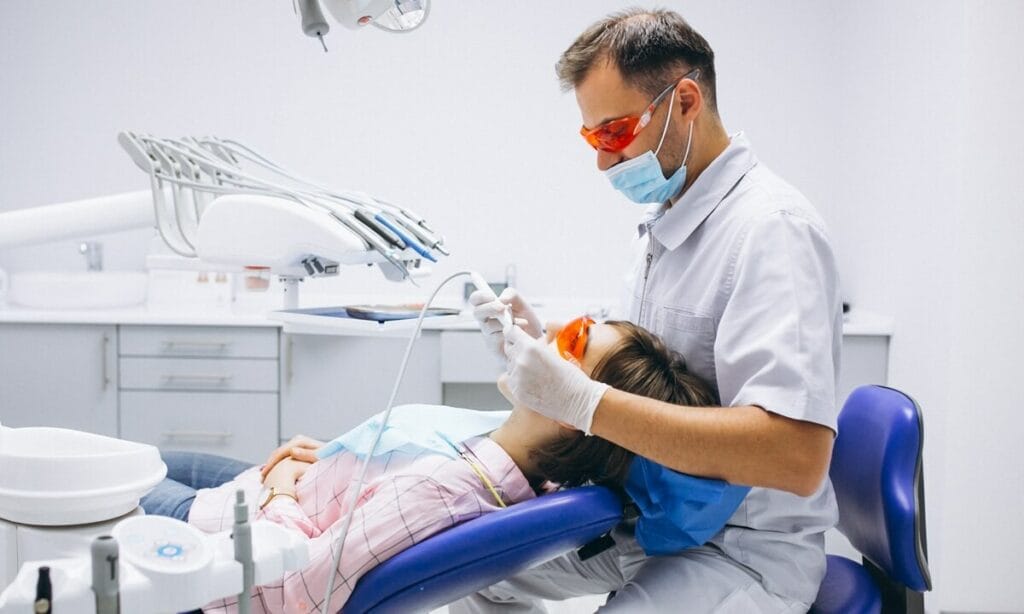 Wypełnienia stomatologiczne - dentysta wykonujący zabieg stomatologiczny u pacjentki