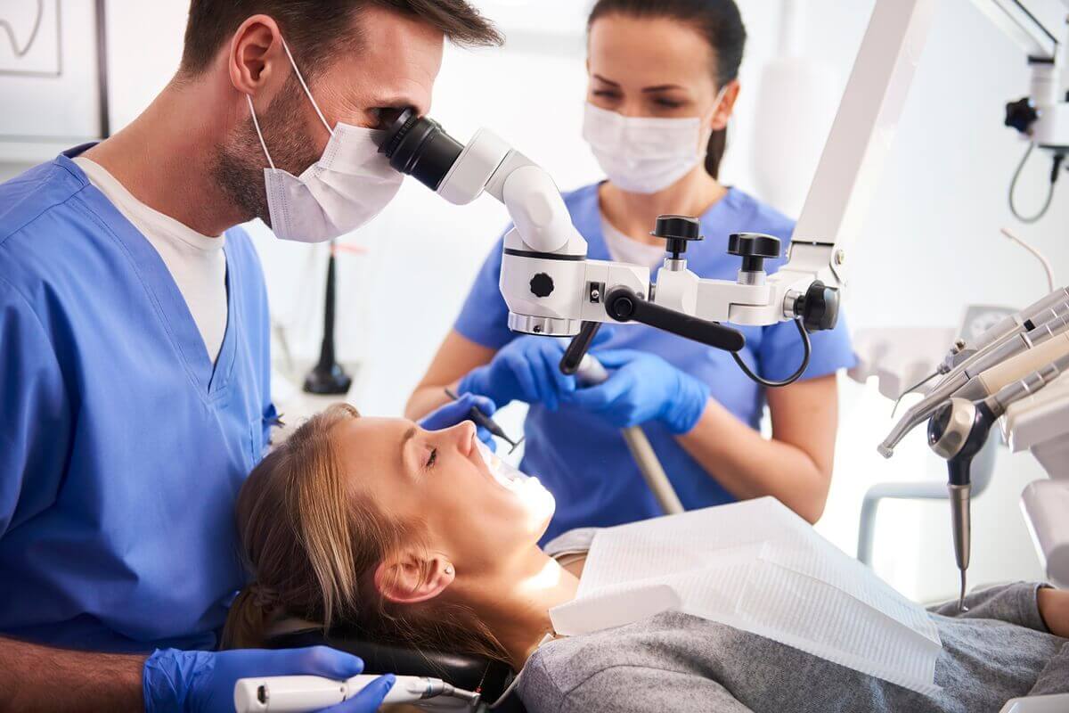 Na czym polega leczenie kanałowe - lekarz dentysta wykonujący leczenie kanałowe pod mikroskopem u pacjentki
